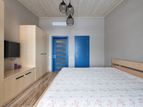 Спалня със светли мебели и две интериорни сини врати